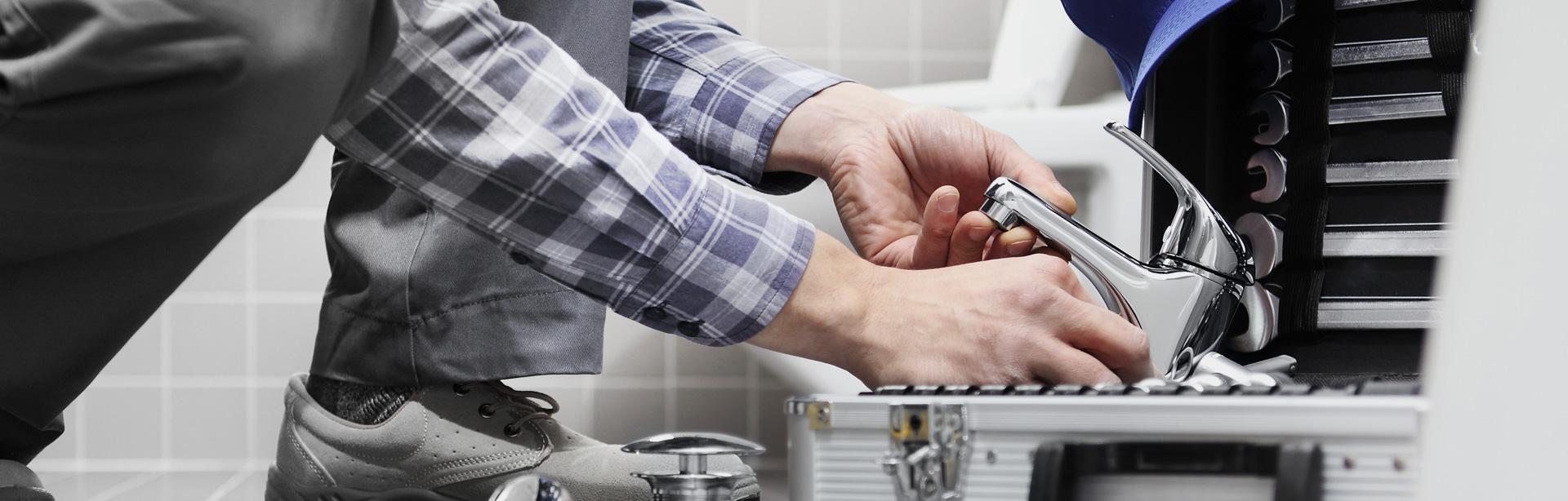 mężczyzna wyjmuje baterię umywalkową ze skrzyni z narzędziami